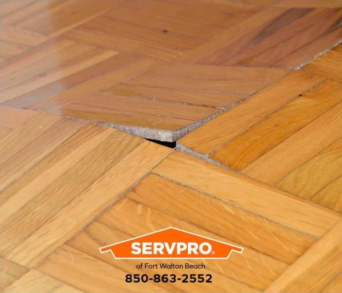 A wood floor shows signs of water damage.