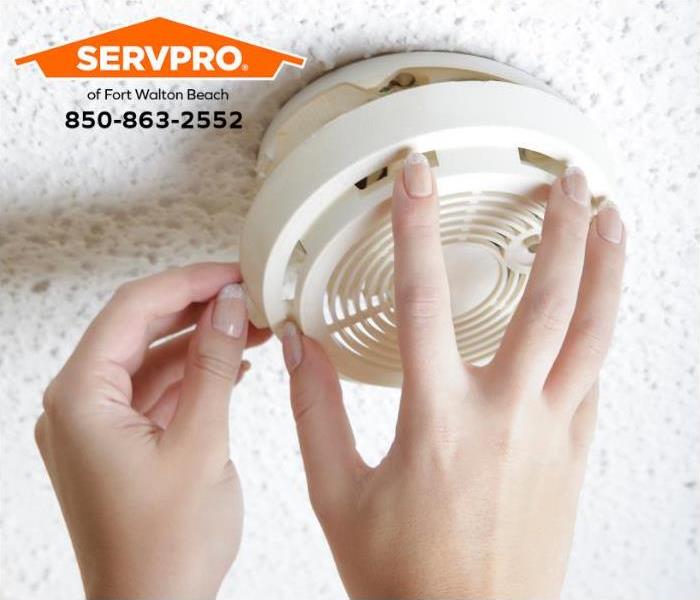 A person is replacing a battery in a smoke alarm.